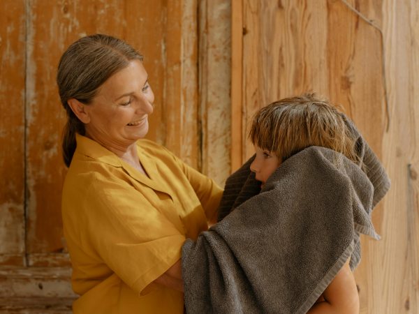 Mujer sonriente secando a un niño con una toalla.