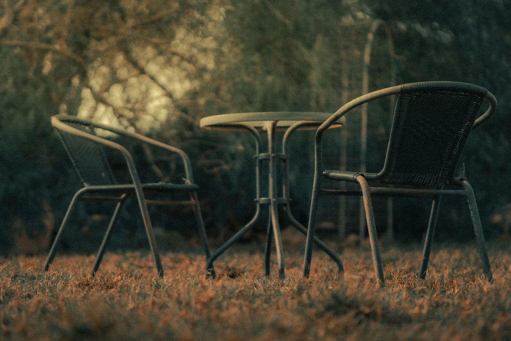 Mesa y sillas vacías en un jardín al atardecer.